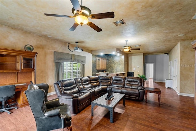 living area featuring visible vents, ceiling fan, baseboards, and wood finished floors