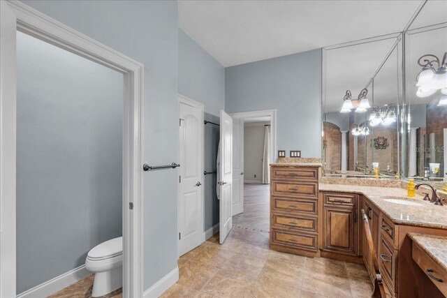 full bath featuring toilet, vanity, and baseboards