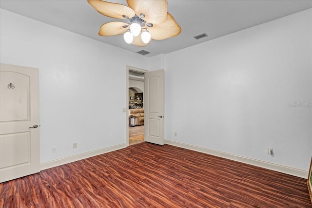 spare room featuring ceiling fan, wood finished floors, visible vents, and baseboards