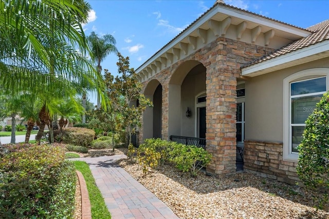 exterior space with stone siding, a porch, a tile roof, and stucco siding