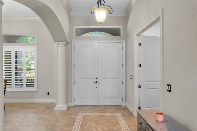 foyer entrance with decorative columns, arched walkways, baseboards, and ornamental molding