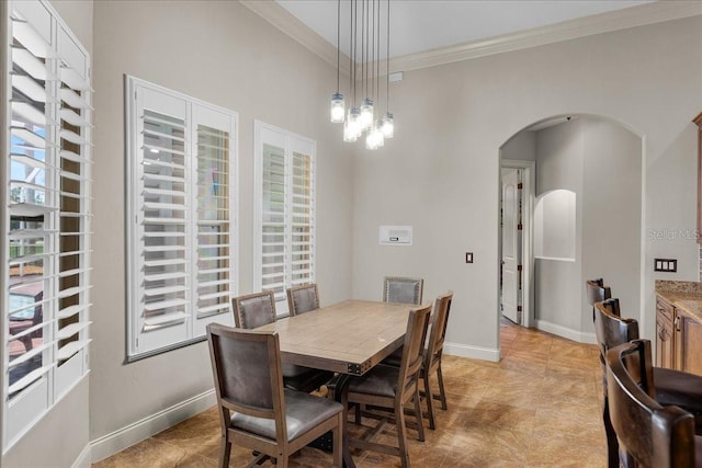 dining space with arched walkways, baseboards, and crown molding