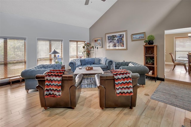 living room featuring ceiling fan, plenty of natural light, light wood-type flooring, and high vaulted ceiling