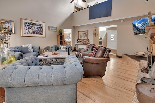 living room featuring a high ceiling, light hardwood / wood-style flooring, and ceiling fan