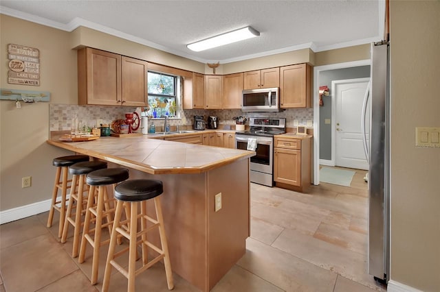 kitchen featuring kitchen peninsula, a kitchen breakfast bar, backsplash, stainless steel appliances, and crown molding