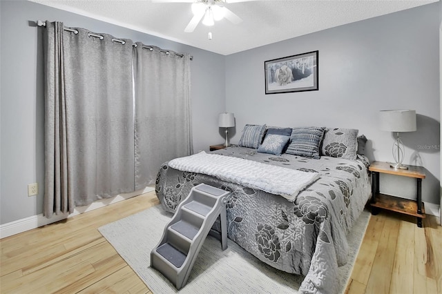 bedroom featuring ceiling fan, wood-type flooring, and a textured ceiling