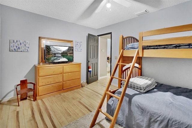 bedroom with a textured ceiling, light hardwood / wood-style flooring, and ceiling fan