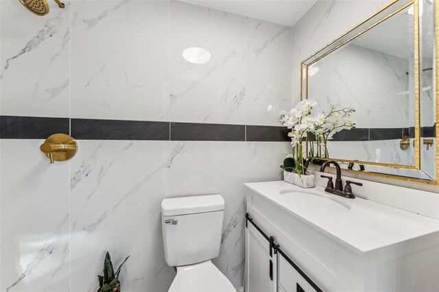 bathroom with vanity, tile walls, and toilet