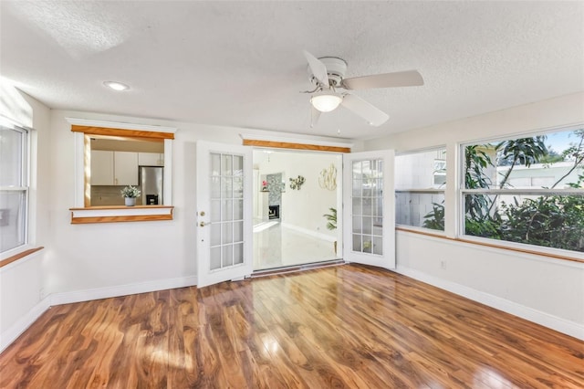 empty room with hardwood / wood-style flooring, ceiling fan, a textured ceiling, and french doors