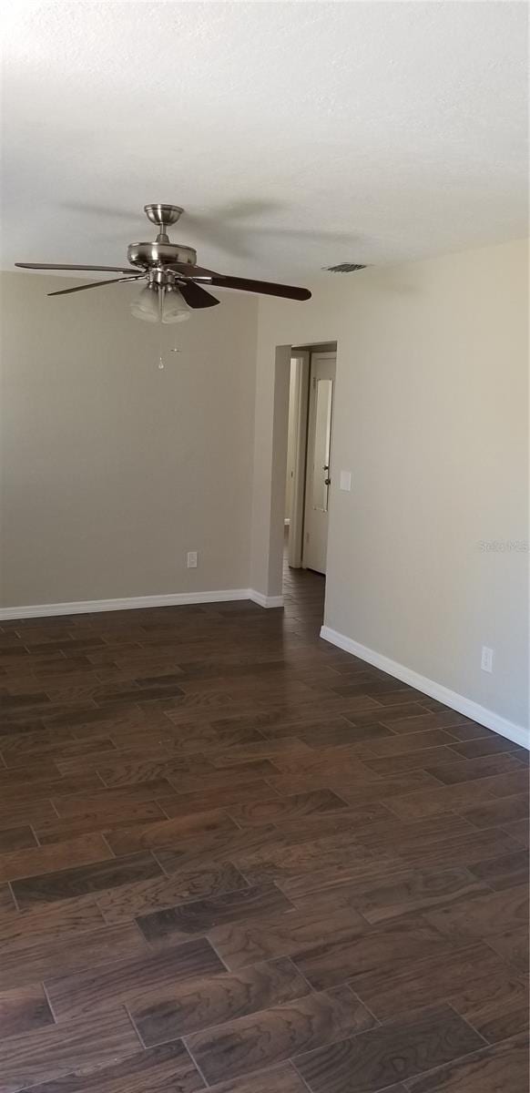 unfurnished room featuring dark wood-type flooring and ceiling fan