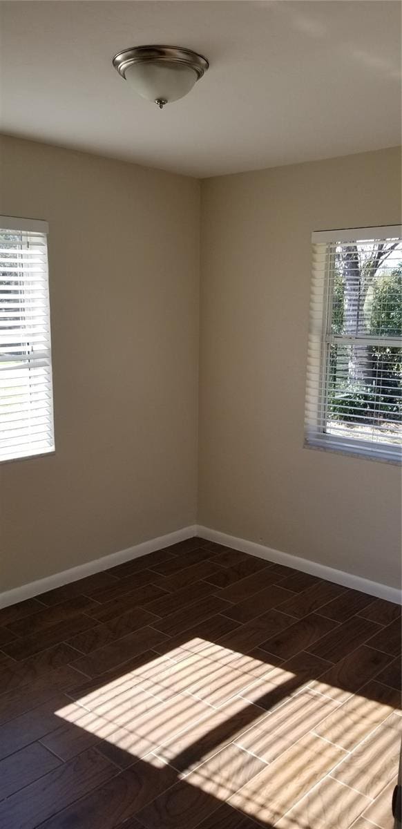 empty room with a healthy amount of sunlight and dark hardwood / wood-style flooring