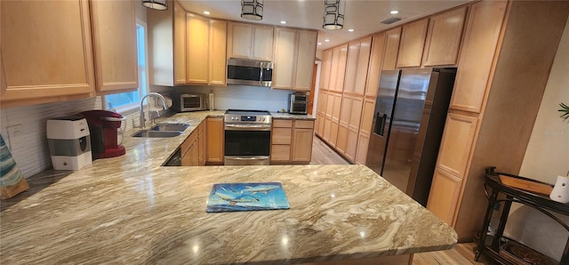 kitchen featuring light stone countertops, sink, hanging light fixtures, stainless steel appliances, and light brown cabinetry