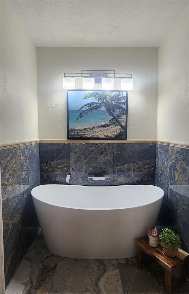 bathroom featuring a textured ceiling, tile walls, and a tub