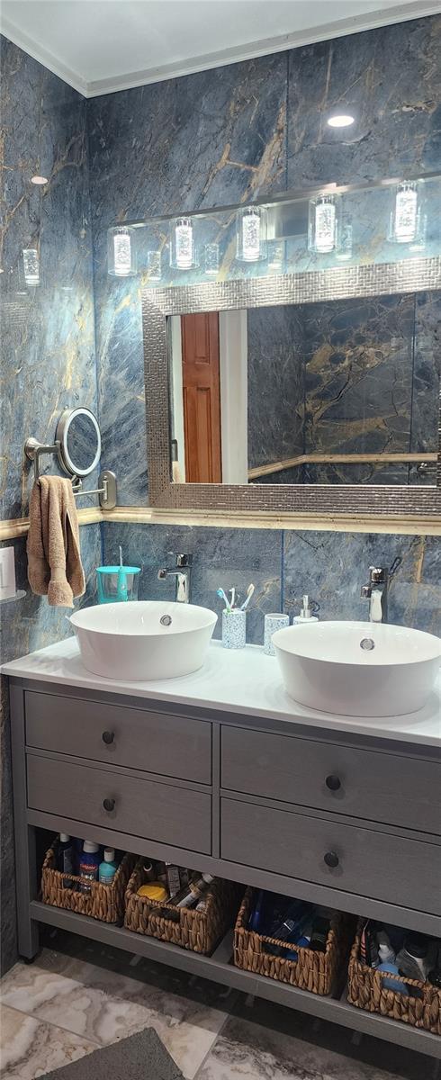 bathroom with decorative backsplash, vanity, and tile walls