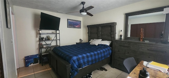 bedroom featuring ceiling fan, light tile patterned floors, and a textured ceiling