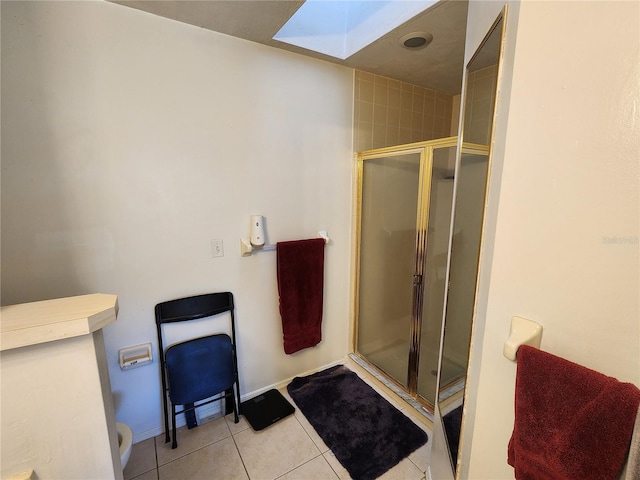 bathroom featuring a skylight, tile patterned flooring, an enclosed shower, and toilet