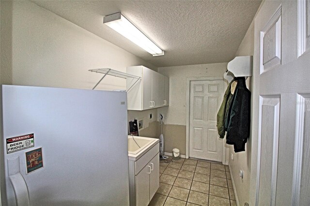 clothes washing area with cabinets, light tile patterned floors, a textured ceiling, and hookup for a washing machine