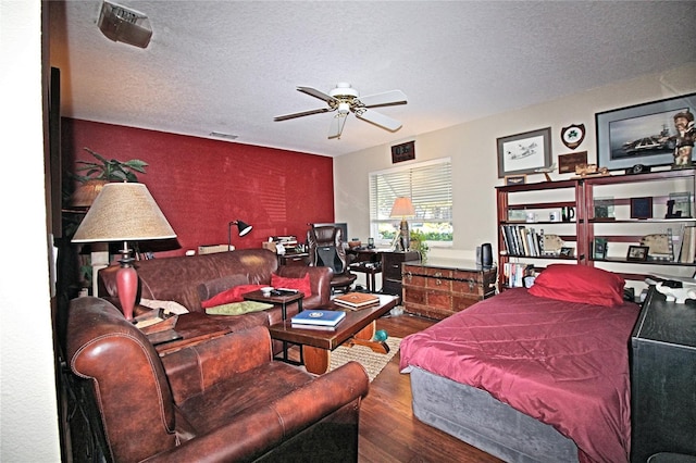 bedroom with ceiling fan, wood-type flooring, and a textured ceiling