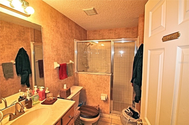 bathroom with vanity, a shower with door, tile patterned floors, toilet, and a textured ceiling