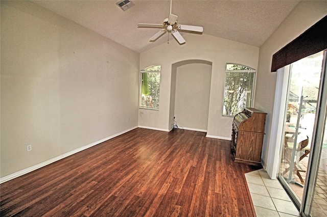 unfurnished room with hardwood / wood-style flooring, ceiling fan, lofted ceiling, and a textured ceiling