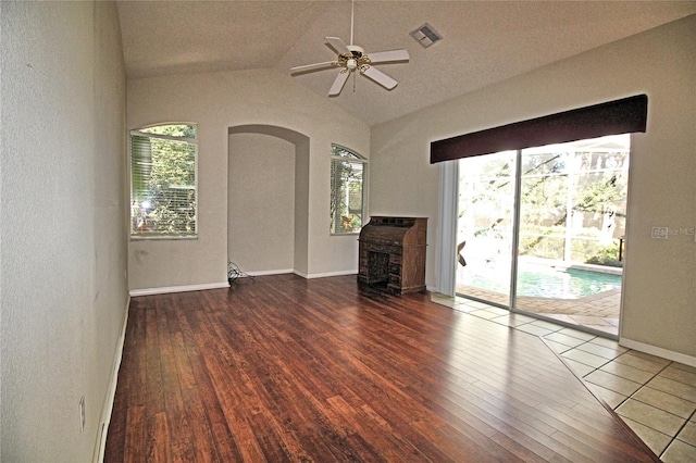 unfurnished living room featuring ceiling fan, dark hardwood / wood-style floors, a wealth of natural light, and vaulted ceiling