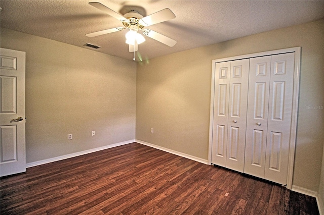 unfurnished bedroom featuring ceiling fan, a closet, dark wood-type flooring, and a textured ceiling