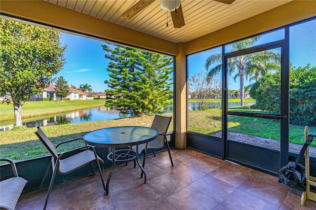 sunroom featuring ceiling fan and a water view