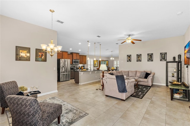 tiled living room with ceiling fan with notable chandelier