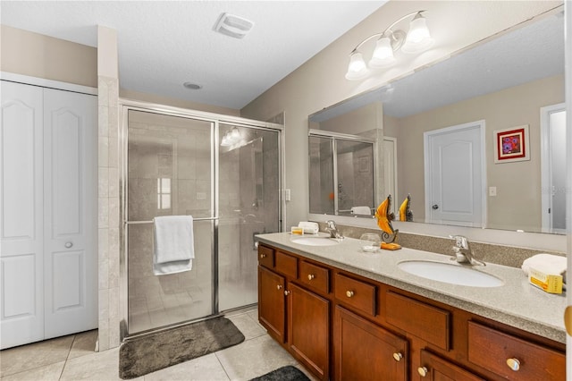 bathroom with tile patterned floors, a shower with door, and vanity