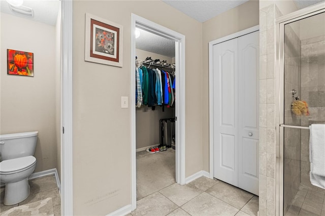 bathroom featuring tile patterned floors, toilet, a textured ceiling, and walk in shower