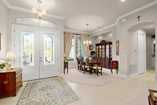 foyer entrance with ornamental molding, an inviting chandelier, light tile patterned floors, and french doors