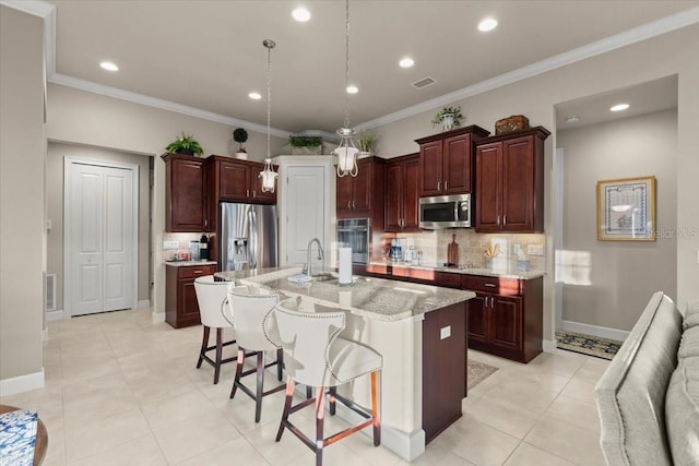 kitchen featuring decorative backsplash, a breakfast bar, appliances with stainless steel finishes, and a center island with sink