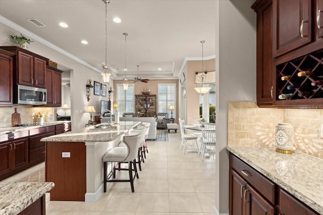 kitchen featuring a kitchen breakfast bar, decorative light fixtures, backsplash, light stone counters, and light tile patterned flooring