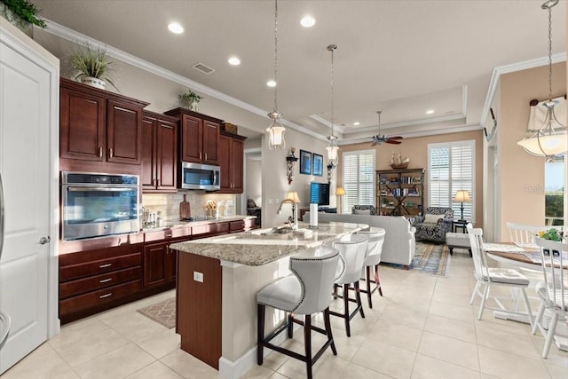 kitchen featuring hanging light fixtures, a center island with sink, stainless steel appliances, and a breakfast bar area