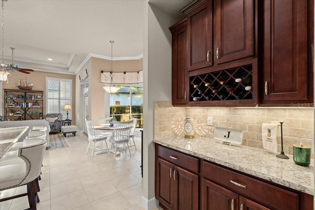 bar featuring crown molding, light stone countertops, light tile patterned floors, decorative light fixtures, and ceiling fan