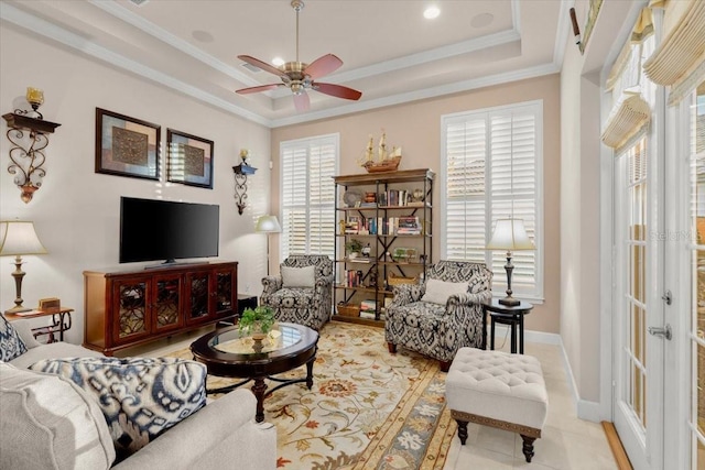 living room featuring ceiling fan, a tray ceiling, ornamental molding, and a healthy amount of sunlight