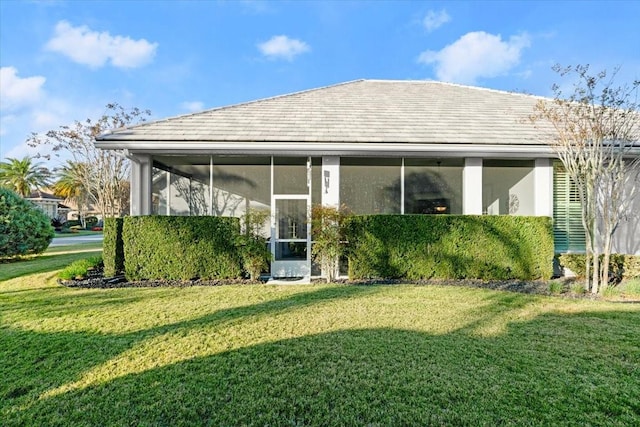 rear view of property with a sunroom and a lawn