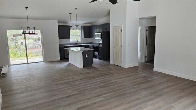 kitchen with appliances with stainless steel finishes, decorative light fixtures, a center island, ceiling fan, and dark wood-type flooring