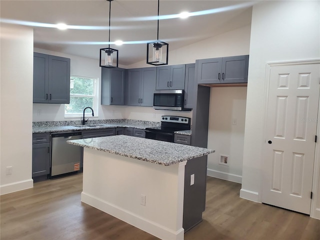 kitchen featuring sink, hanging light fixtures, stainless steel appliances, light stone counters, and a kitchen island