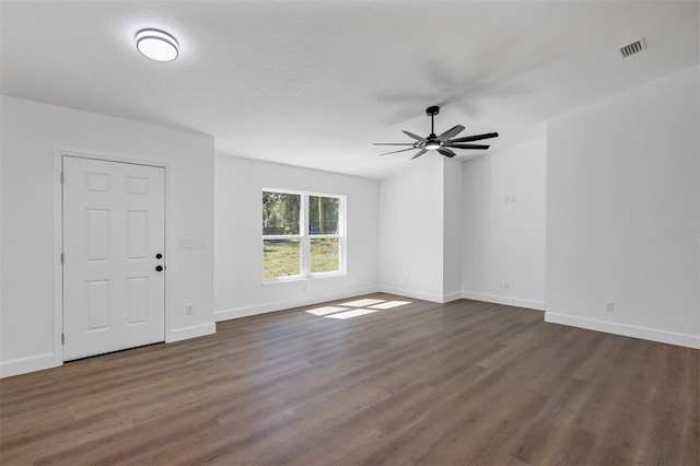 interior space featuring baseboards, visible vents, a ceiling fan, dark wood-style flooring, and a textured ceiling