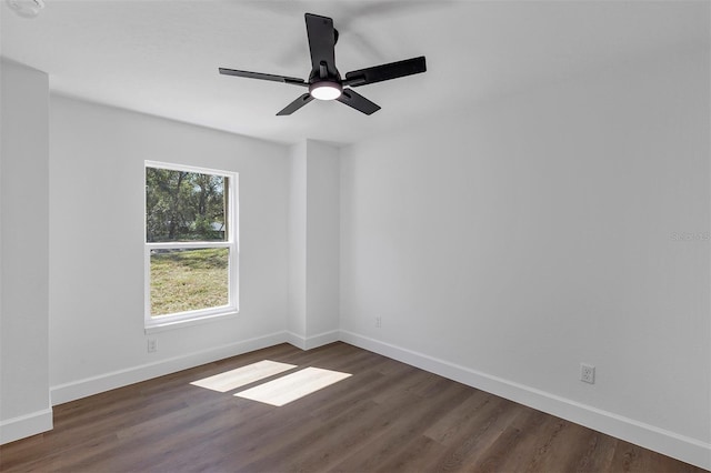 empty room featuring dark wood-style flooring, a ceiling fan, and baseboards