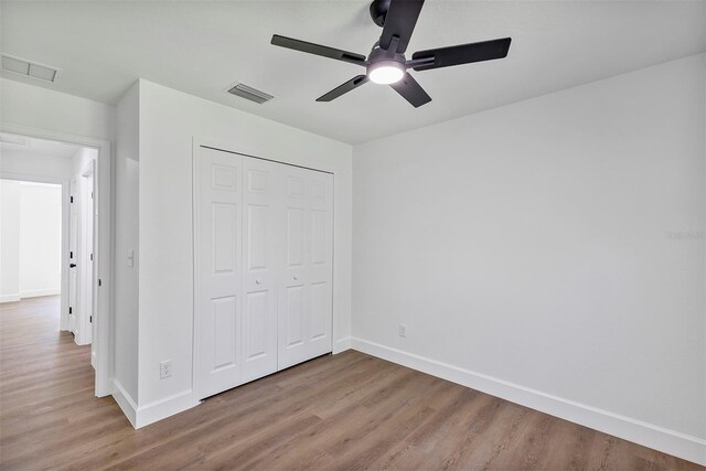 unfurnished bedroom with a closet, visible vents, and wood finished floors