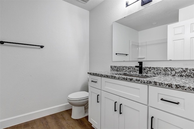 bathroom with toilet, wood finished floors, visible vents, vanity, and baseboards