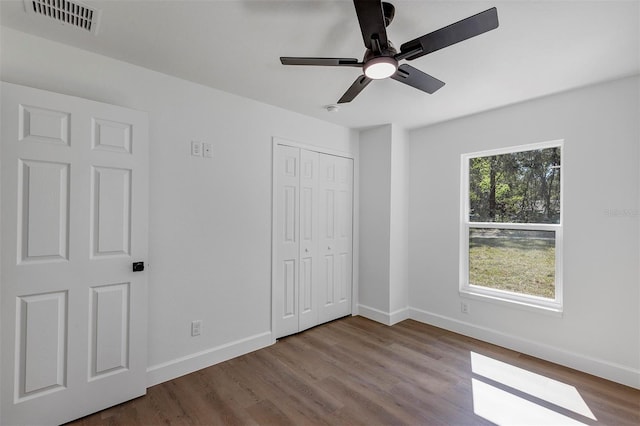 unfurnished bedroom featuring a closet, wood finished floors, visible vents, and baseboards