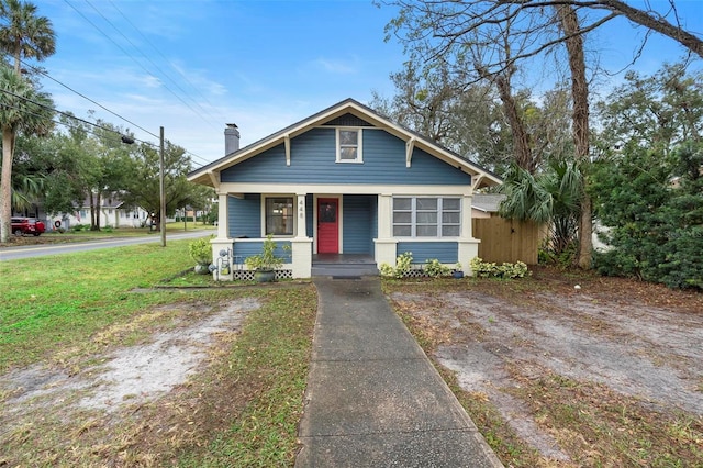 bungalow featuring covered porch and a front yard