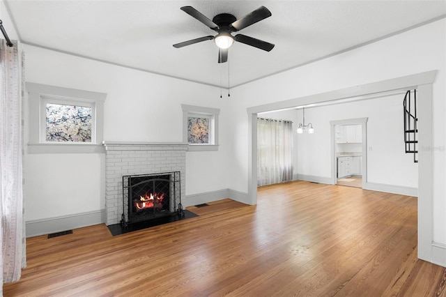 unfurnished living room featuring a fireplace, hardwood / wood-style floors, and ceiling fan with notable chandelier