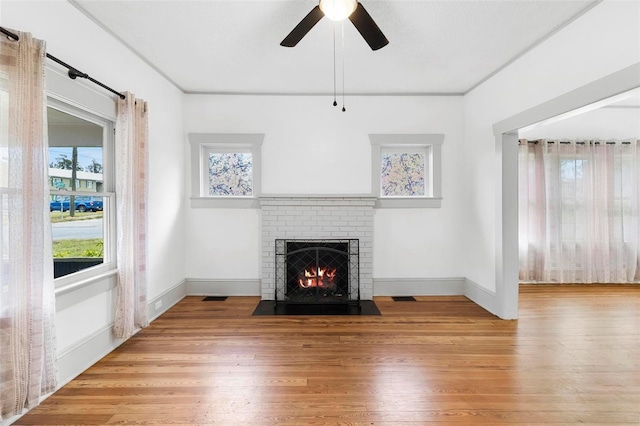 unfurnished living room with light wood-type flooring, a brick fireplace, and ceiling fan