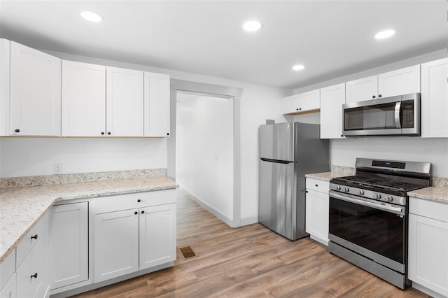 kitchen with white cabinetry, light hardwood / wood-style flooring, light stone countertops, and appliances with stainless steel finishes