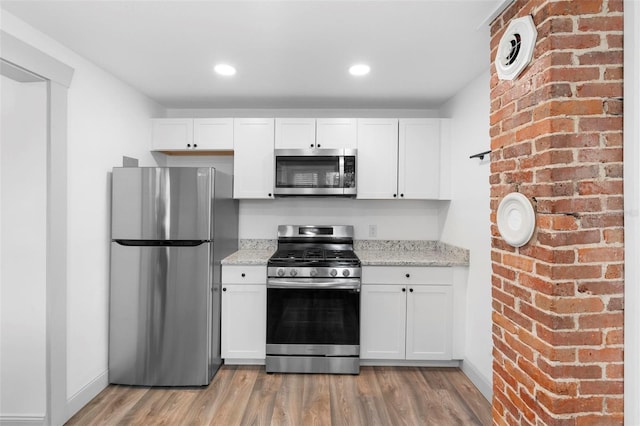 kitchen with light stone counters, white cabinetry, and appliances with stainless steel finishes