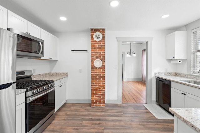 kitchen with light stone countertops, stainless steel appliances, white cabinets, dark hardwood / wood-style floors, and hanging light fixtures